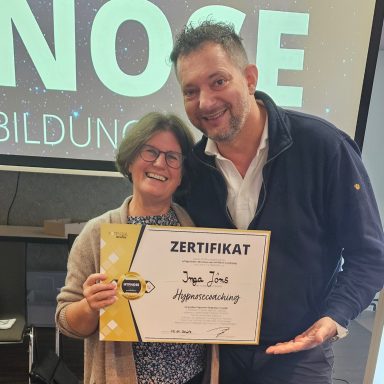 Zwei Personen halten ein Zertifikat und lächeln in die Kamera.