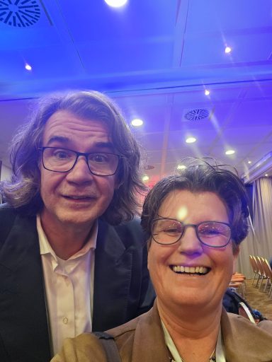 Lächelnde Personen stehen in einem hell erleuchteten Raum, fröhliche Atmosphäre.